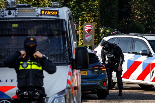Schwer bewaffnete Polizeibeamte patrouillieren am Tatort in Overasselt