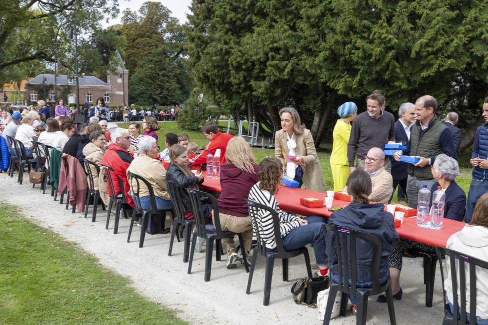 Das Bild zeigt eine lange Tafel in einem Park. Prinzessin Claire spricht mit einigen Menschen, die daran teilnehmen