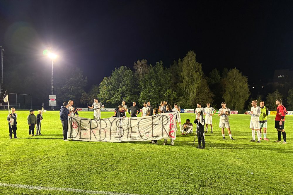 Spieler des RFC St. Vith mit Banner, auf dem "Derbysieger" zu lesen ist