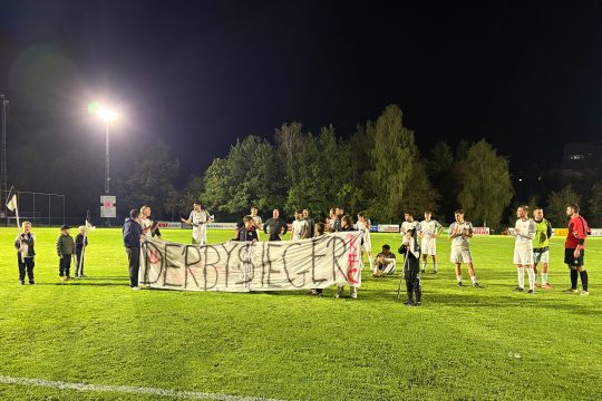 Spieler des RFC St. Vith mit Banner, auf dem "Derbysieger" zu lesen ist