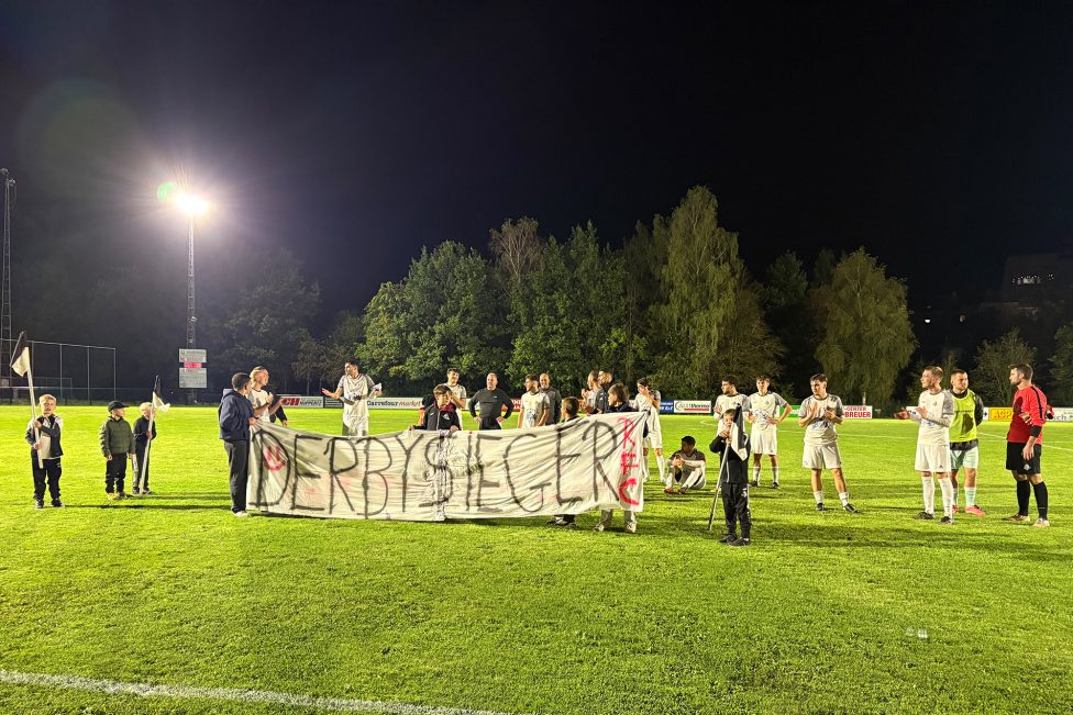 Spieler des RFC St. Vith mit Banner, auf dem "Derbysieger" zu lesen ist