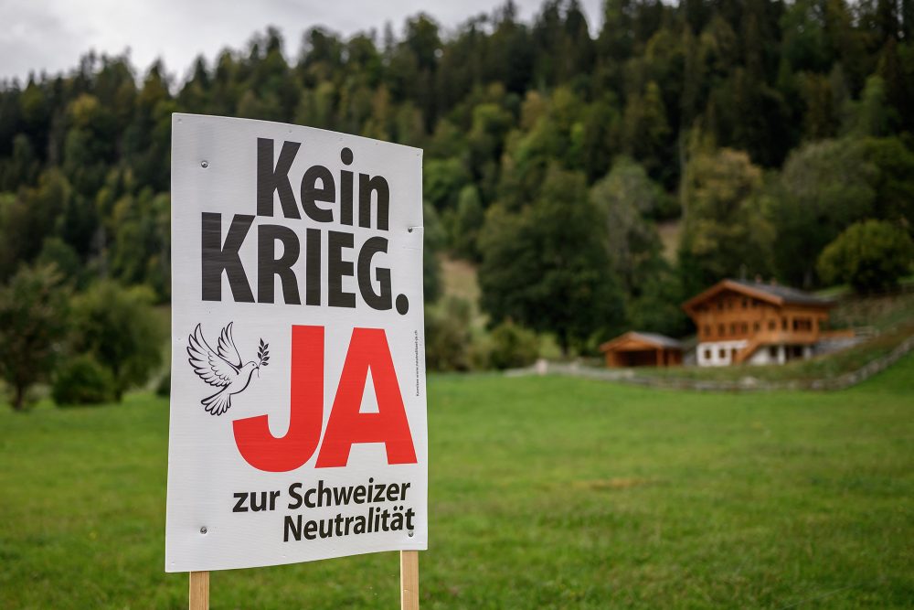 EIn Kampagnenposter mit dem Schriftzug "Kein Krieg - Ja zur Schweizer Neutralität" steht am Wegesrand