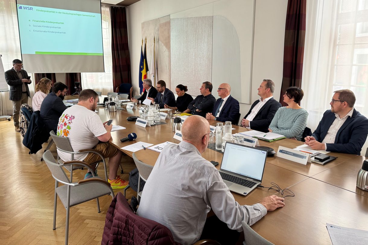 Vertreter von Regierung, WSR und Presse sitzen am Konferenztisch und blicken auf eine Leinwand