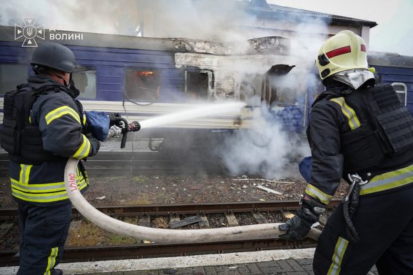 Feuerwehrleute besprühen einen beschädigten Zugwaggon mit Wasser