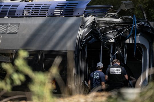 Ermittler der Polizei stehen vor dem entgleisten Zug