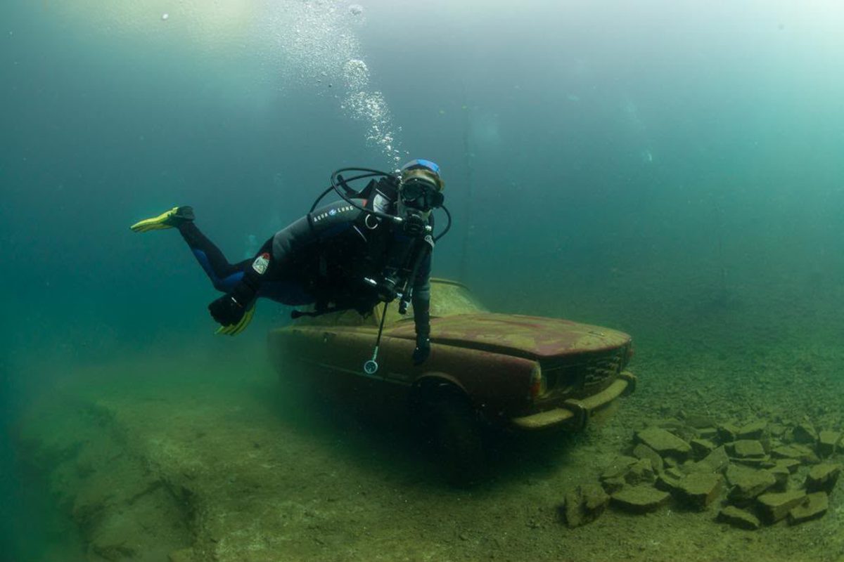 Taucher im Wasser vor Autowrack