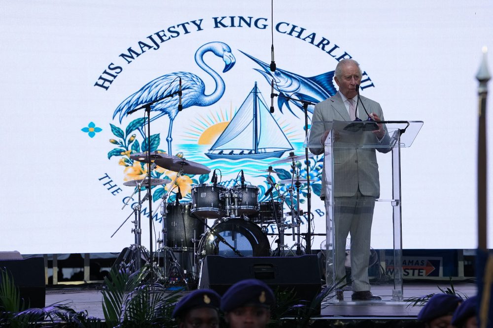 König Charles III. hält auf einer Bühne eine Ansprache, im Hintergrund steht ein Schlagzeug