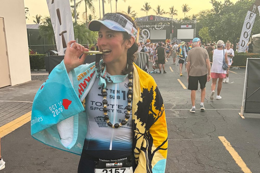 Jana Backes beißt in die Ironman-Medaille