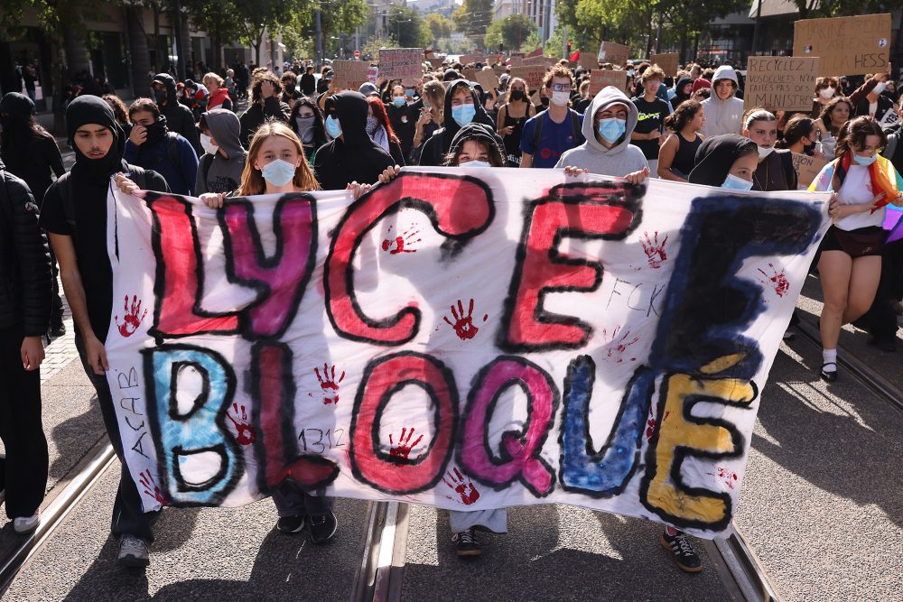 Schüler demonstrieren in Lyon, sie halten ein bemaltes Transparent in den Händen, auf dem in Französisch "Lycée Bloqué" steht