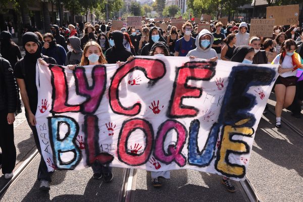 Schüler demonstrieren in Lyon, sie halten ein bemaltes Transparent in den Händen, auf dem in Französisch "Lycée Bloqué" steht