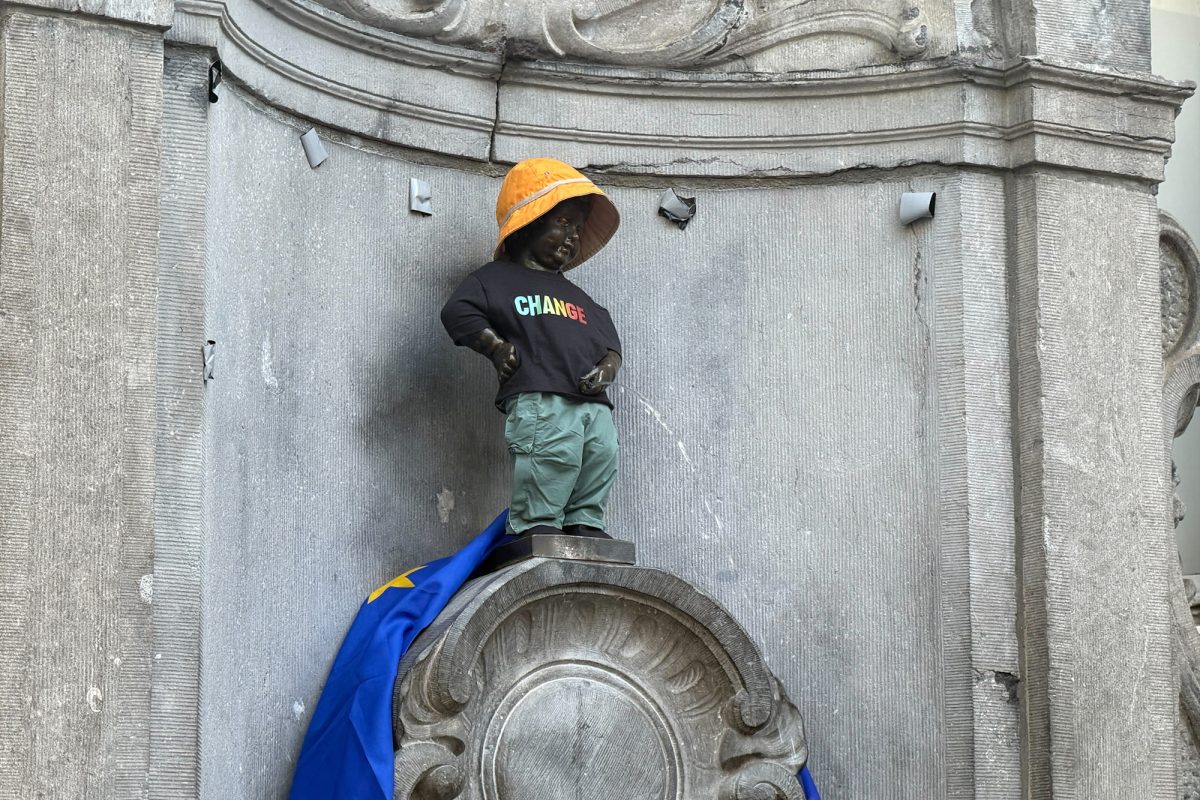 Das Manneken Pis mit orangem Schlapphut und schwarzem Pullover mit dem Aufdruck "Change"