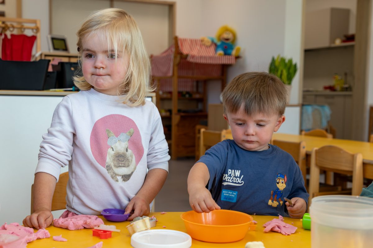 Zwei kleine Kinder formen etwas aus Knete