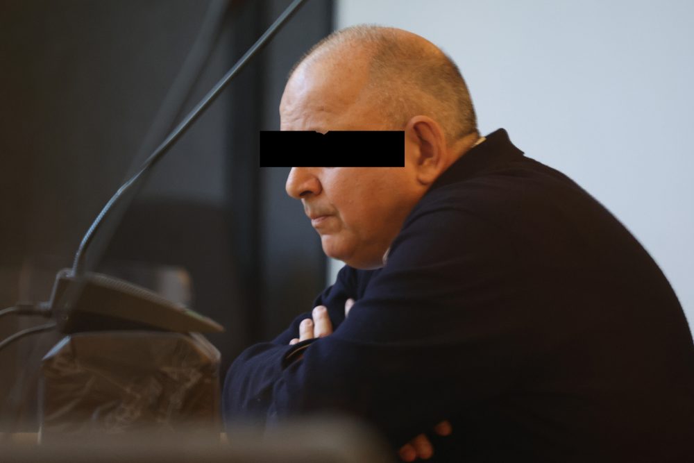 Nicolas Ullens de Schooten sitzt im Gerichtssaal, auf dem Bild ist ein Balken eingefügt worden, der seine Augen unkenntlich macht