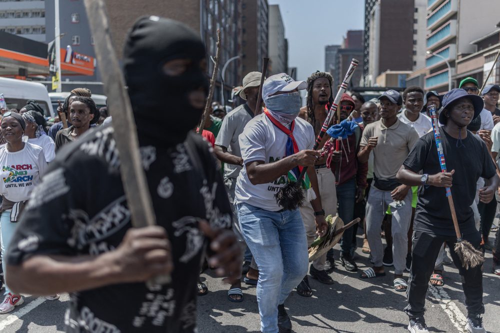 vermummte Demonstranten schwingen Baseball-Schläger