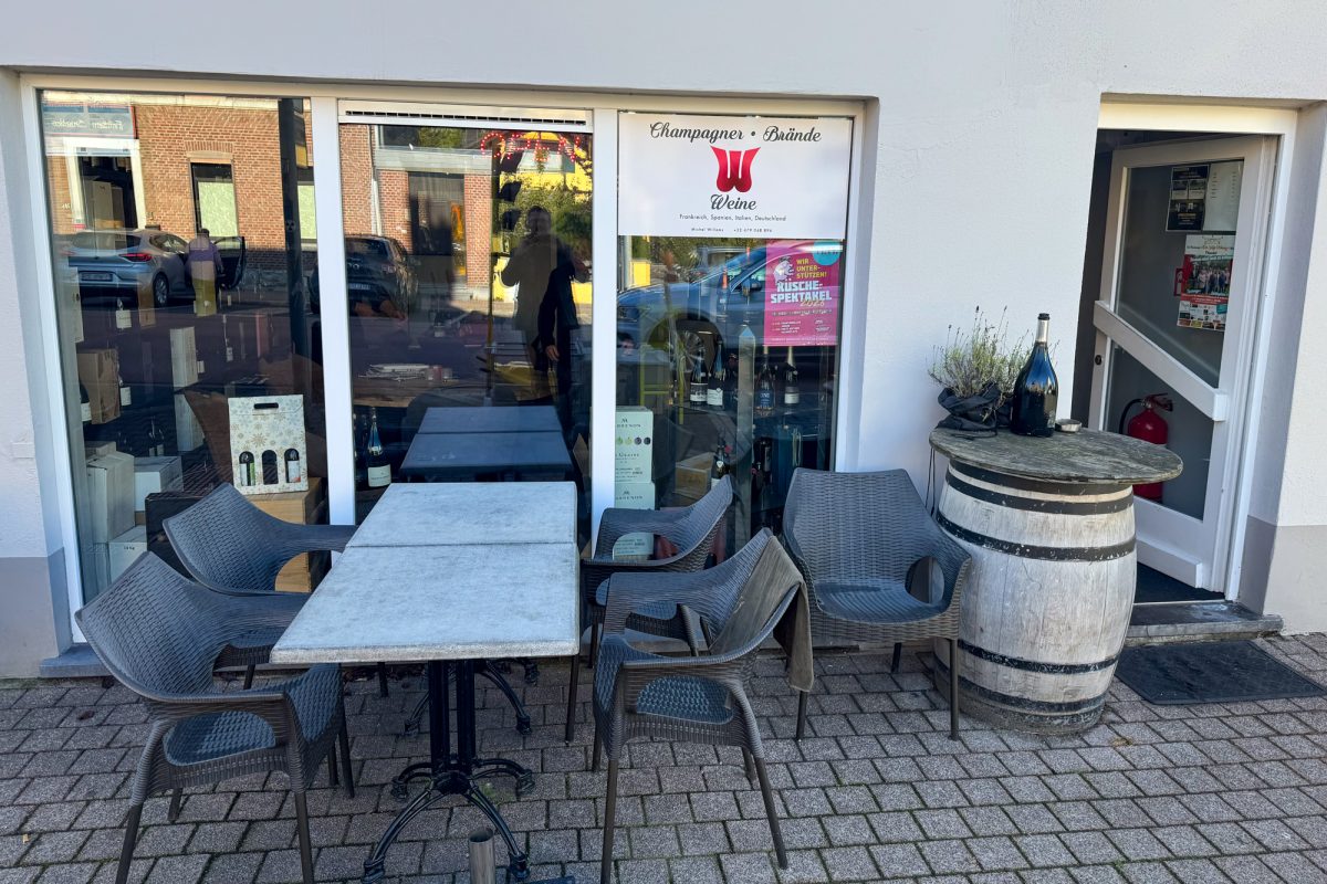 Außenansicht der Vinothek an der Lütticher Straße, vor dem Lokal stehen Tische mit Stühlen