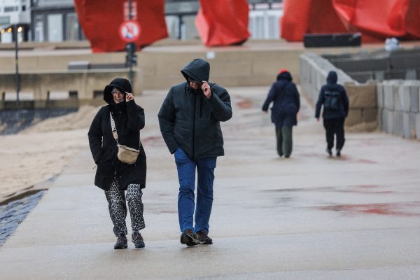 Zwei Spaziergänger halten ihre Kapuzen fest vor dem Sturm