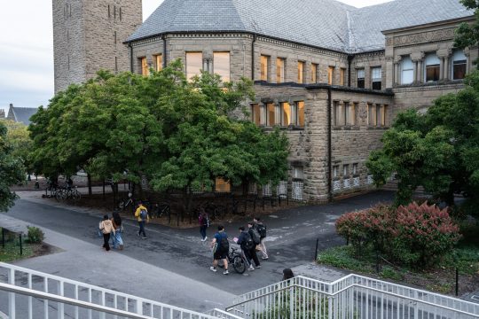Hauptgebäude der US-Universität Cornell, davor gehen einige Studierende entlang