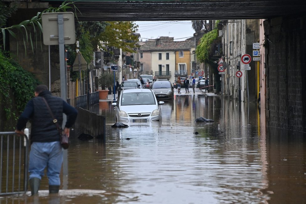 Ein Man in Gummistiefeln watet durch das Wasser auf einer überfluteten Straße