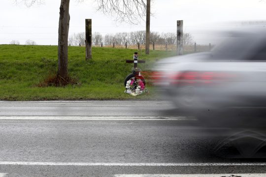 Auto fährt an einem Wegekreuz in Gedenken an einen Verkehrstoten vorbei