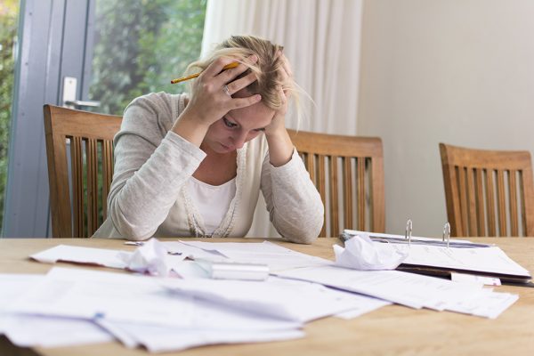 Deprimierte Frau vor Schuldenberg